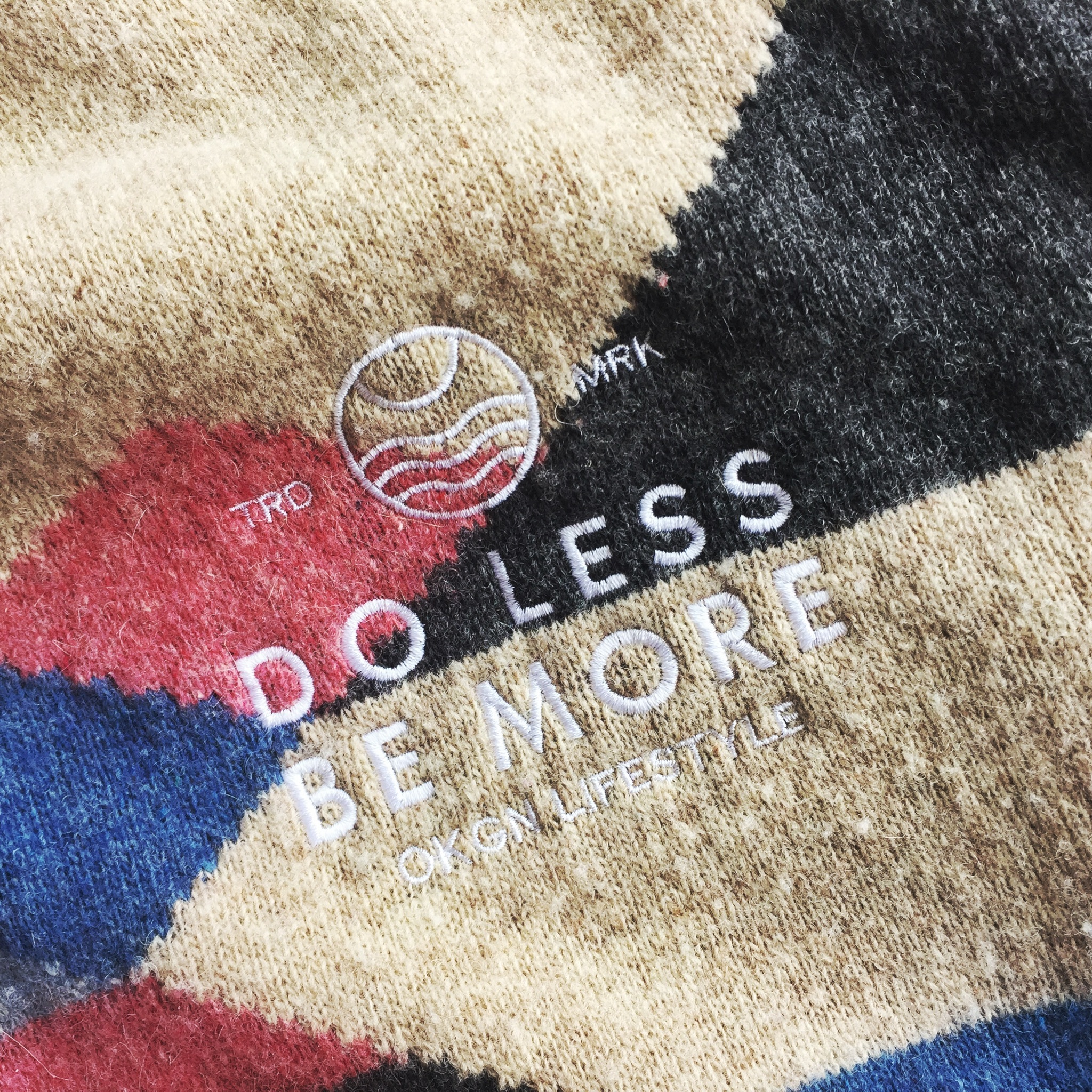 close up photo of "Do Less, Be More" slogan on Okanagan Lifestyle-branded thrifted wool sweater