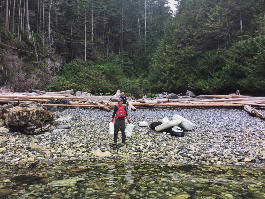 Photo of Ocean Legacy volunteer on the shores of Texada Island, British Columbia carrying plastic expanded polystyrene foam waste from the beach during a cleanup mission.