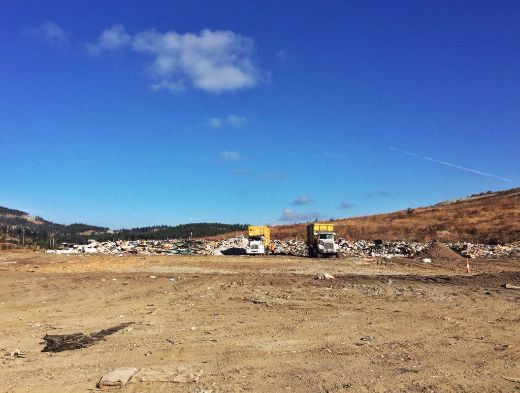 photo of a landfill on a blue-sky day in Kelowna, British Columbia, with waste and garbage being dumped by commercial haulers.