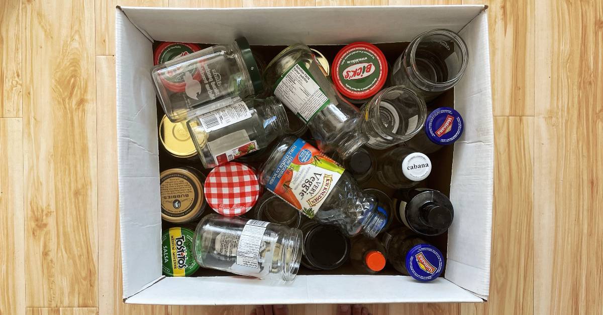A top-down view of a box of glass jars with lids.