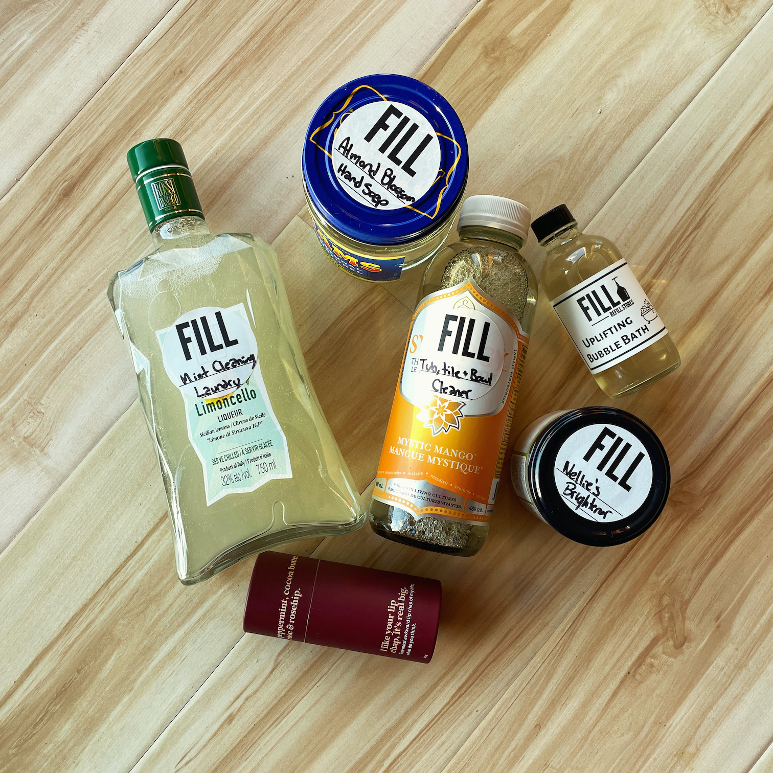 A variety of glass jars from a community jar program laying on a wooden floor.