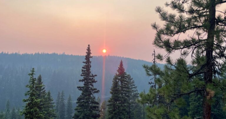 Wildfire smoke casts an orange hue as the sun sets over Idabel Lake.