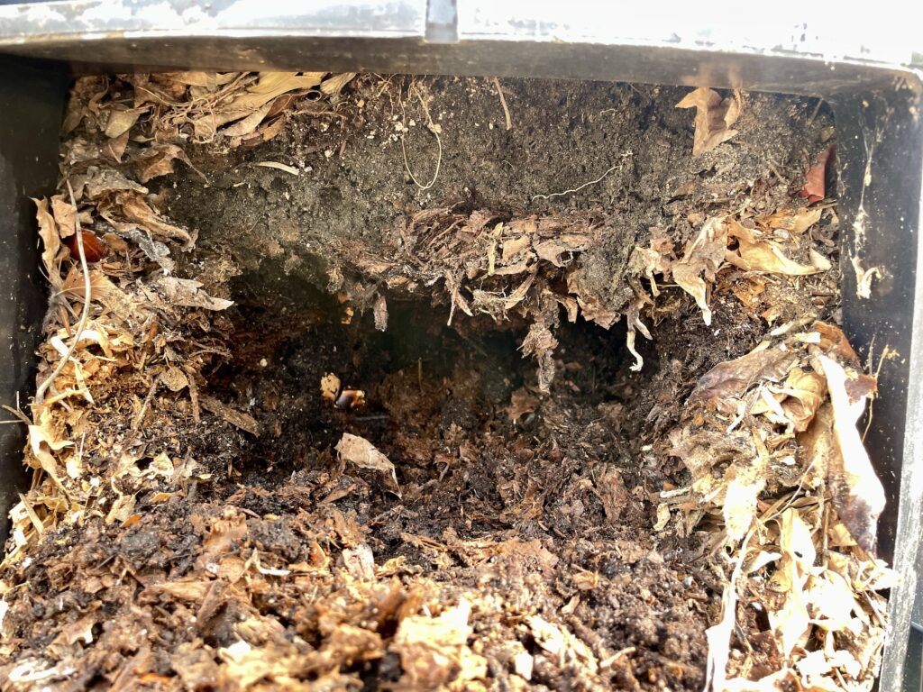 Compost spills out of a home compost pile.